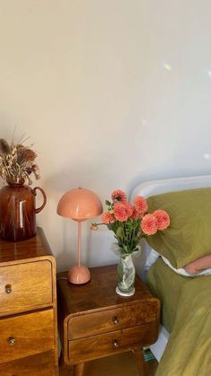 a bed room with a neatly made bed and some flowers on the nightstand next to it