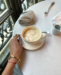 a person sitting at a table with a cup of coffee and silverware on it