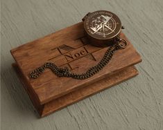 a wooden box with a compass and chain on it sitting on top of a table