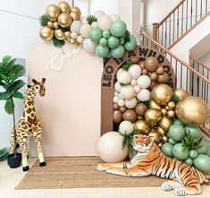 there is a fake tiger next to balloons and a giraffe in the room