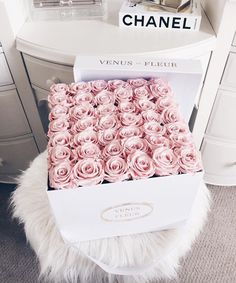 a white box filled with pink roses on top of a table