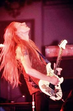 a woman with long red hair playing an electric guitar in front of a microphone and keyboard