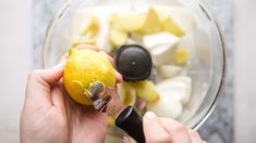 someone is peeling an orange in a blender filled with ingredients for making lemonade