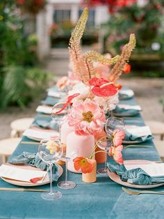 the table is set with blue linens and pink flowers