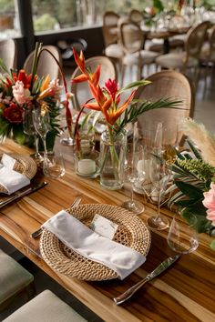 a wooden table topped with lots of flowers and place settings on top of each other