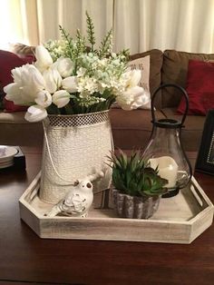 a tray with flowers and candles on top of a wooden table next to a couch