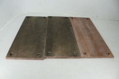 three pieces of wood sitting on top of a white floor next to each other with metal rivets