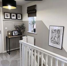 a hallway with pictures on the wall and paintings on the walls, along with a white railing