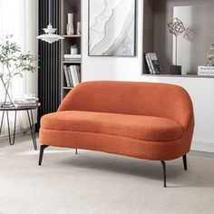 an orange couch sitting in a living room next to a table and bookshelf