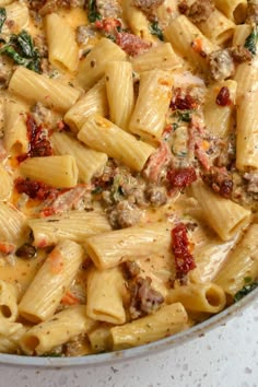 a pan filled with pasta and meat on top of a white countertop next to a red checkered towel