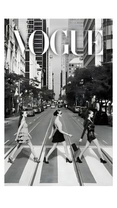 three women crossing the street in front of a large advertisement for louis vuitti