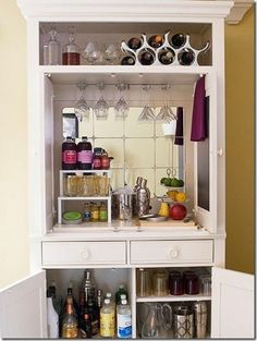 an open cabinet with bottles and glasses on it