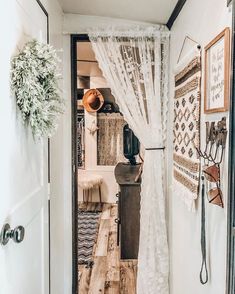 an open door leading into a room with curtains and rugs on the wall,