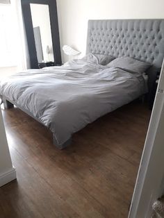 a bed sitting on top of a hard wood floor next to a window in a bedroom