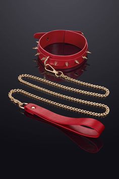 a red leather bracelet with spikes and chains attached to it, on a black background