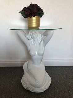 a glass table with a vase on top of it and a fish statue underneath the base