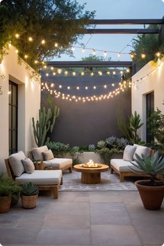 an outdoor living area with couches, lights and potted plants on the patio