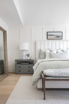 a bed with white linens and pillows in a bedroom next to pictures on the wall