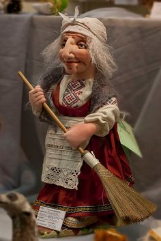 a statue of a woman holding a broom next to a stuffed animal on a table