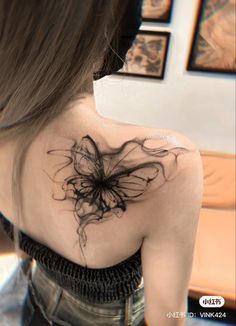 the back of a woman's shoulder with an abstract tattoo design on her left shoulder