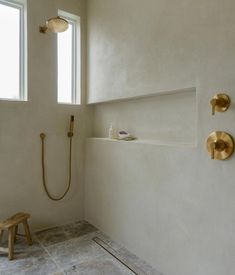 a white bathroom with gold fixtures on the shower head and hand held faucet