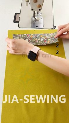 a woman is using a sewing machine to sew something on a yellow table cloth