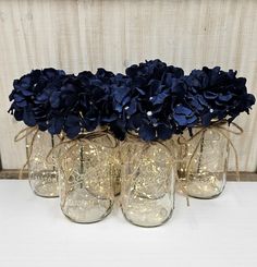 four glass jars with blue flowers in them