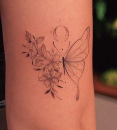 a woman's leg with flowers and a butterfly tattoo on the side of her thigh