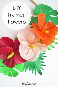 some paper flowers are hanging on a wall with the words diy tropical flowers above them