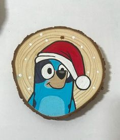 a blue bird with a santa hat on it's head sitting in front of a piece of wood