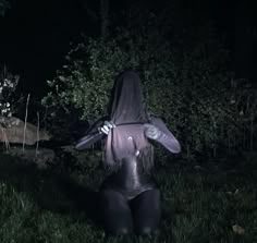 a woman dressed as a creature sitting in the grass with her hands on her hips