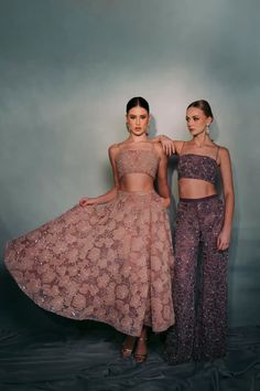 two women standing next to each other in matching outfits