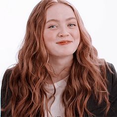 a woman with long red hair wearing a black jacket