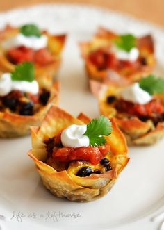 small appetizers on a white plate topped with sour cream and black olives