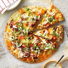 a pizza sitting on top of a white plate next to a bowl of dipping sauce