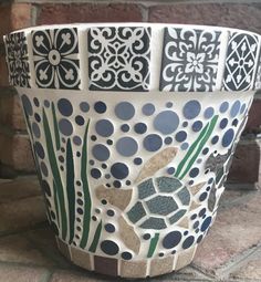 a ceramic flower pot sitting on top of a stone floor next to a brick wall