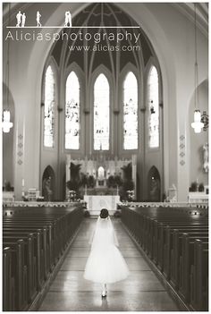 black and white photograph of a woman walking down the aisle of a church with her dress blowing in the wind