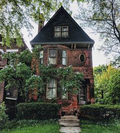 an old brick house with ivy growing on it's windows and steps leading up to the front door