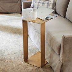 a coffee table with a laptop on it next to a couch in a living room