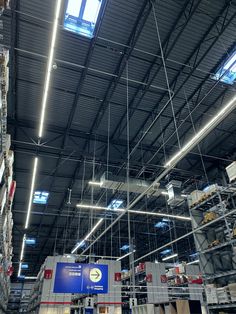 the inside of a large warehouse with lots of shelves and lights hanging from the ceiling