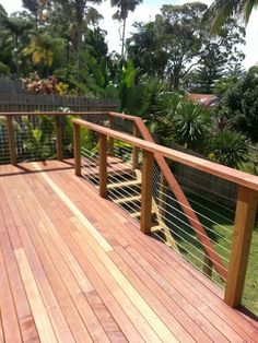 a wooden deck with metal railing and trees in the background