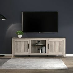 a large flat screen tv mounted on top of a wooden entertainment center in a living room