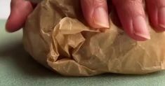 a person's hand holding onto a piece of brown paper