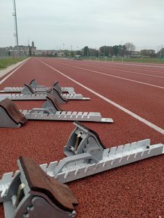 several metal brackets laying on the ground at an outdoor track surface with buildings in the background