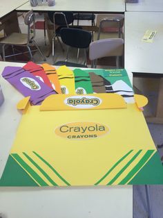 the crayola box is sitting on the table in front of some chairs and desks