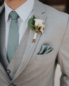 a man in a gray suit with a boutonniere on his lapel