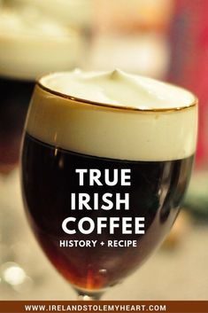 a close up of a wine glass with liquid in it and the words true irish coffee history + recipe