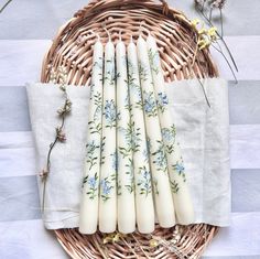 six candles sitting on top of a table next to a wicker basket with flowers