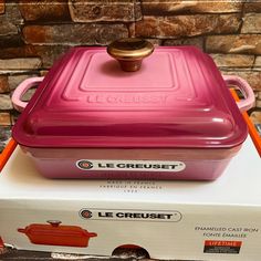 a pink le creuset sitting on top of a box