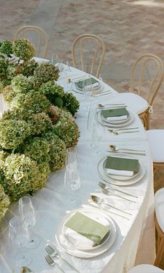 the table is set with plates, silverware and green napkins for an elegant dinner